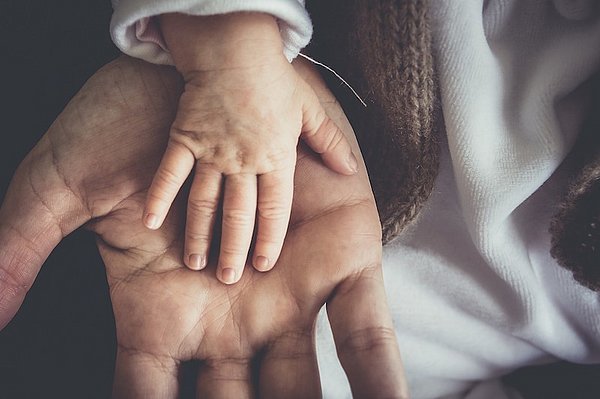 On the image, there is the hand of a small child on the hand of an adult. This image visualizes what it feels like to release anger and resentment.