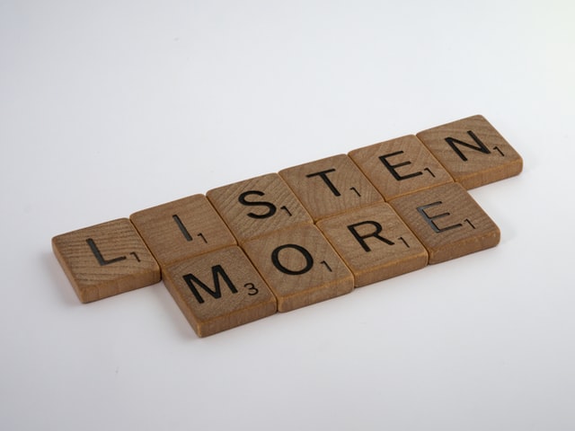 On the image, there are scrabble tiles saying 'Listen more'