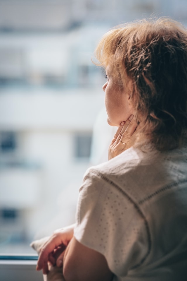 On the image there is a woman who looks worried, like she is holding in her emotions. She is caucasian and has shoulderlong hair.