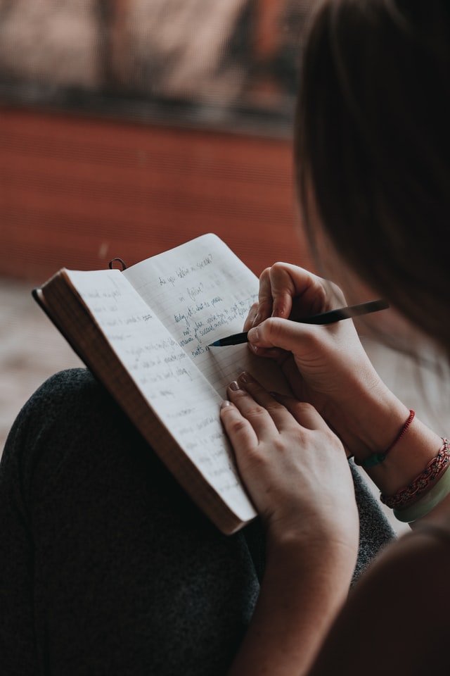 On the image, there is a woman tackling her inner critic through the work. She is writing in her diary.