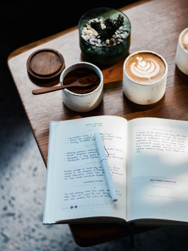 On the image, there is a table with a journal on it. It looks like the person is writing information about the laws of the universe in it.