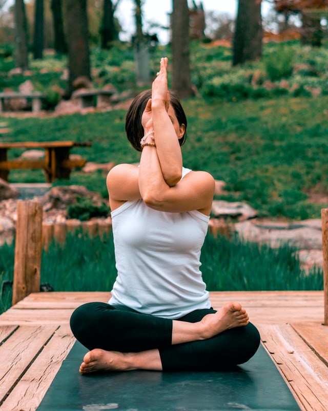 On the image, there is a woman sitting in yoga pose to become spiritual. She intertwines her hands into a creative namaste greeting. Photo credits: Erik Brolin