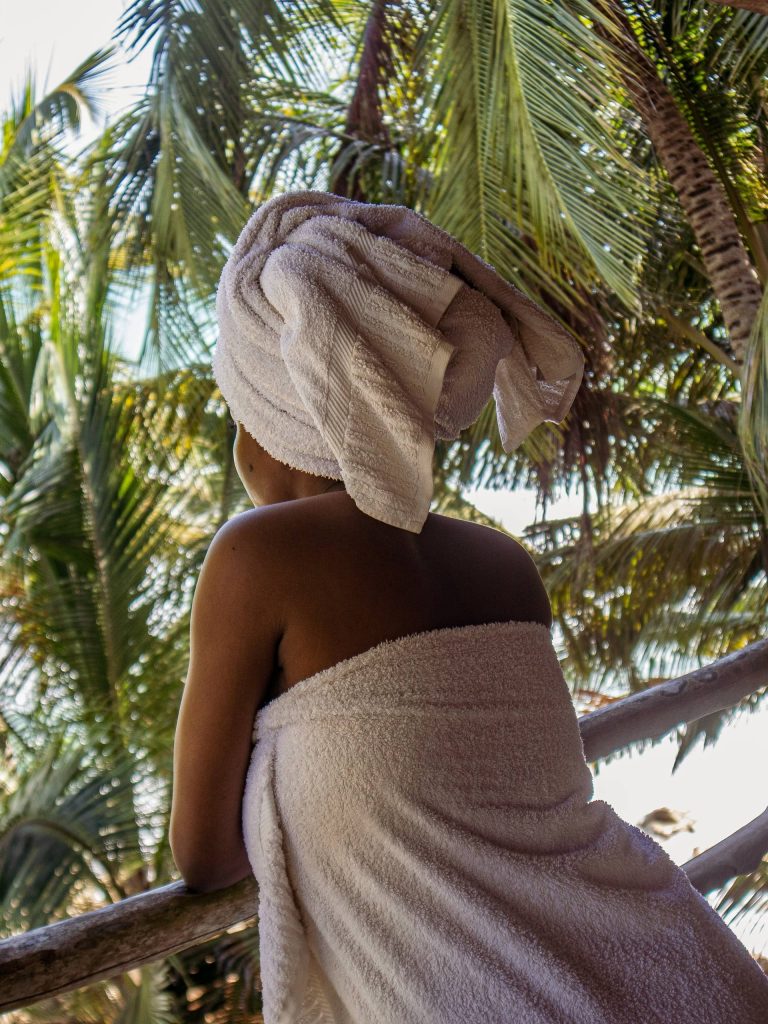 A Highly Sensitive African American woman is wrapped in a comfy white towels on both her body and head. She is looking out from her balcony after taking a relaxing bath. Photo Credit: Joshua Oluwagbemiga