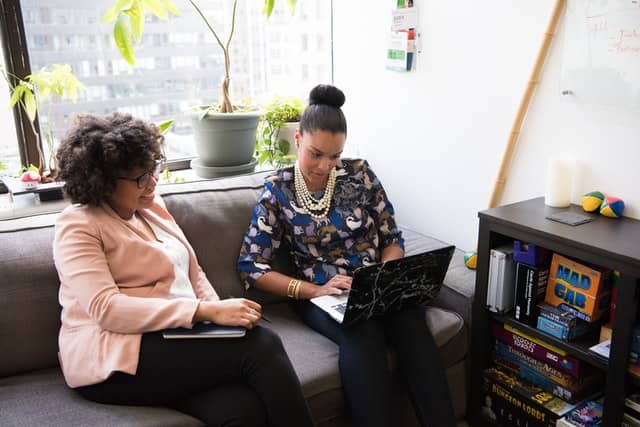 This image by wocintechchat.com shows two women working together. It shows that in order to achieve work-family balance, highly sensitive people need to reach out for help.