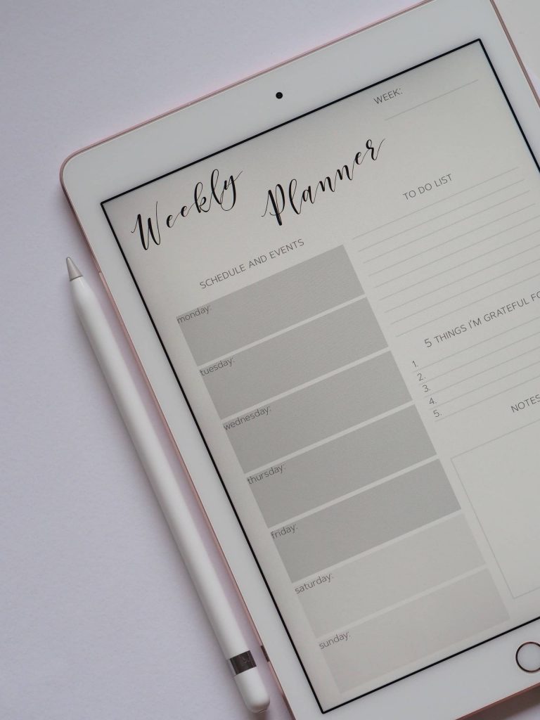 A tablet displaying a weekly planner is laying on a desk. Photo Credit: Jess Bailey