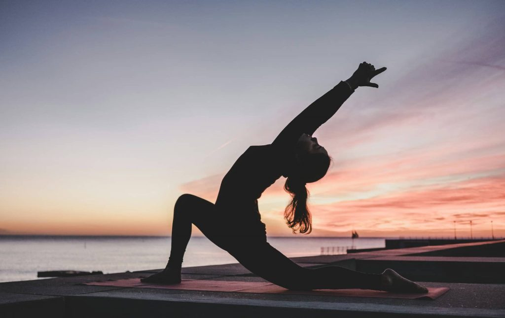 This image by Kike Vega shows a woman doing Yoga sports by sunset to reduce stress.